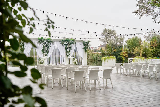 istock Wedding ceremony with arch, orchid flowers, chairs and bulb in forest outdoors, copy space. Wedding decorations 1305146633