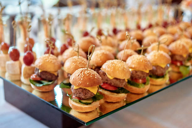 istock Buffet table with mini hamburgers and canape at luxury wedding reception, copy space. Serving food and appetizers at restaurant. Catering banquet table 1305146647