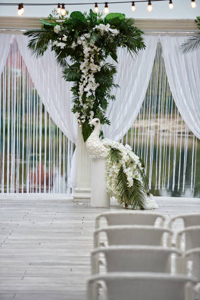 istock Wedding ceremony with arch, orchid flowers, chairs and bulb in forest outdoors, copy space. Wedding decorations 1305146649