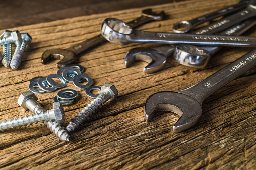 Metal working tools. Wrenches and screws on a wooden background.
