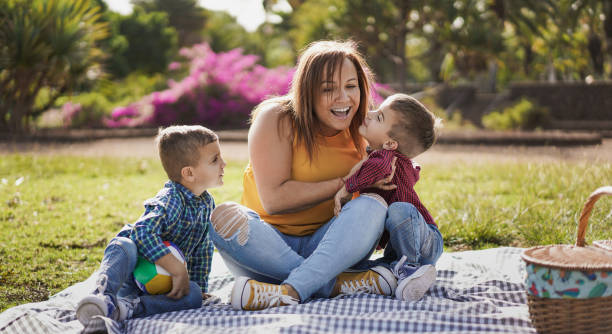 young latin mother and little twin sons having playful time outdoor in nature park - mother and children love - life events laughing women latin american and hispanic ethnicity imagens e fotografias de stock