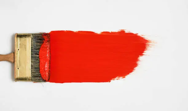 Photo of Brush with red paint lies on a white background, top view, paint samples before work, choice of paints