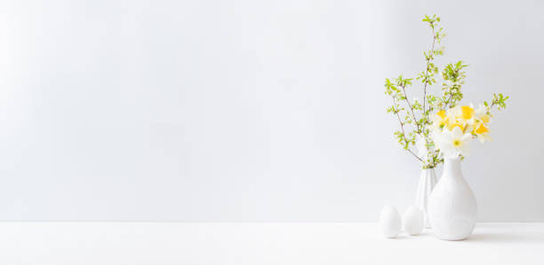 istock Home interior with easter decor. Daffodils in a vase, spring flowers on a light background 1305153750