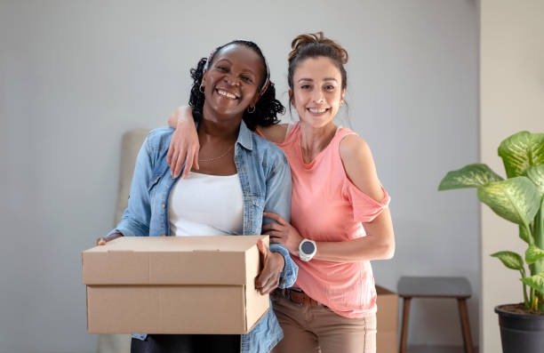 istock Female flatmates are packing things into cardboard boxes, getting ready for moving a new house 1305155164