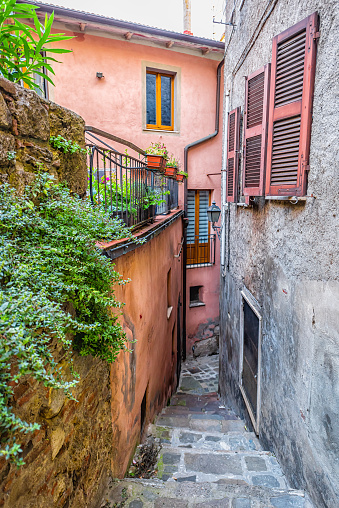 Chiusi, Italy road narrow empty lane alley street in small historic town village in Tuscany colorful wall of houses and garden plants