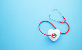Healthcare And Medicine Concept - Red Stethoscope and White Heart Shape Sitting On Blue Background