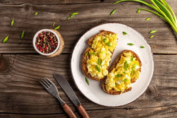 Scrambled eggs with green onion on wheat rye wholemeal crispy bread, homemade, healthy breakfast or brunch. Homemade meal, banner, menu recipe place for text, top view stock photo
