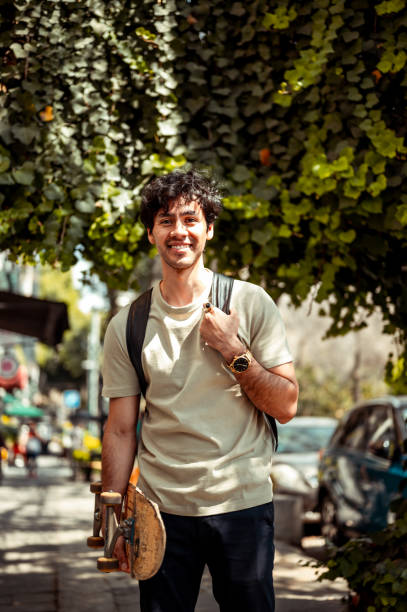 istock Happy young man holding skateboard 1305160066