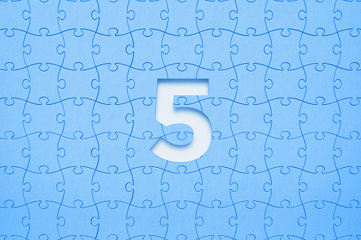 Blue jigsaw puzzle pieces forming a cut out number five on white background. Horizontal composition with copy space. Solution concept.