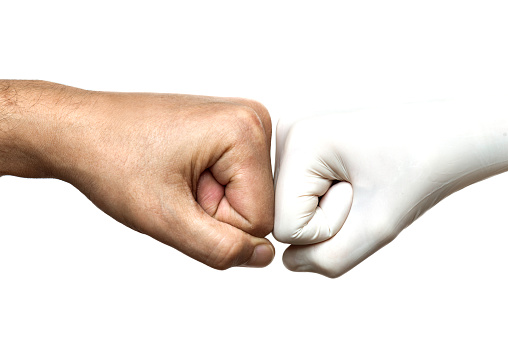 Two unrecognizable caucasian peoples fits are touching each other in front of white background. One is wearing white a protective glove.