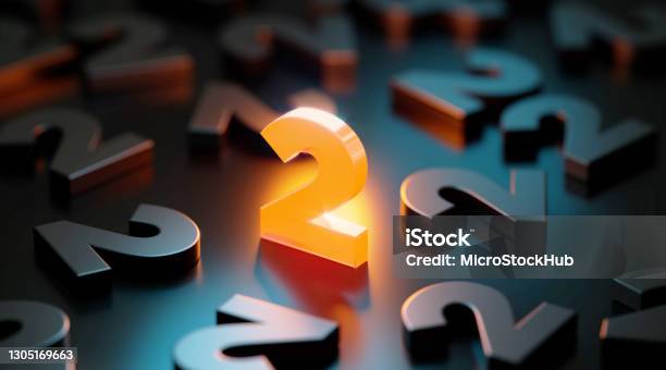 Yellow Number Two Glowing Amid Black Number Twos On Black Background Stock Photo - Download Image Now