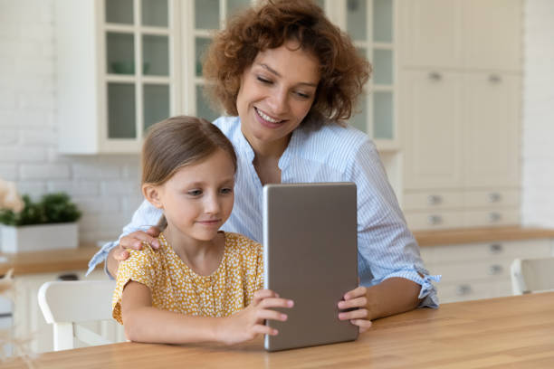 istock Happy mother and small girl use tablet computer at kitchen 1305169682