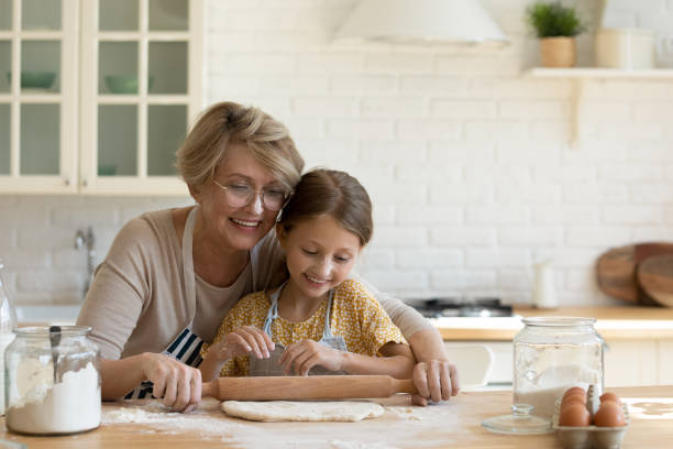 istock Older female nanny rolling dough cooking bakery with little child 1305169729