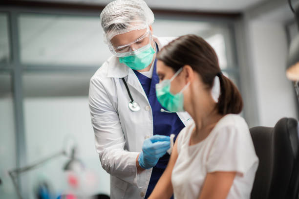 A young woman in a mask decided to get vaccinated against the coronavirus during the pandemic by an experienced doctor in the laboratory stock photo