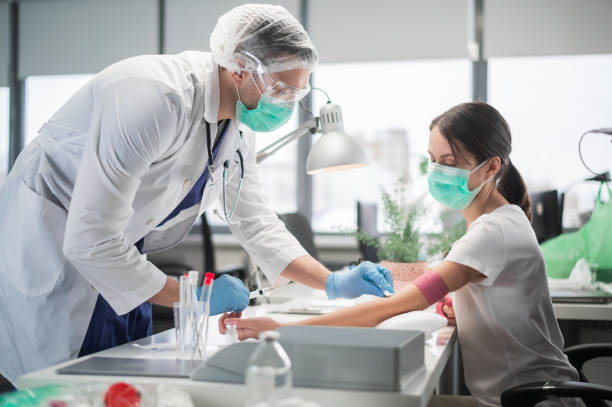 In a private clinic nurse a man puts a tourniquet on the arm of a female patient and takes blood from a vein for analysis stock photo