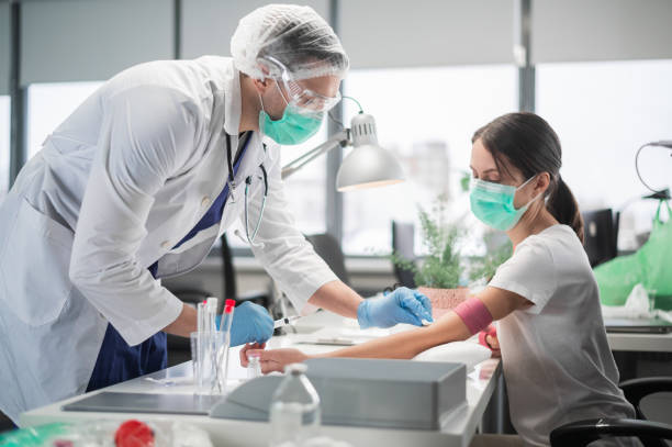 in a private clinic nurse a man puts a tourniquet on the arm of a female patient and takes blood from a vein for analysis - syringe healthcare and medicine vaccination nurse imagens e fotografias de stock