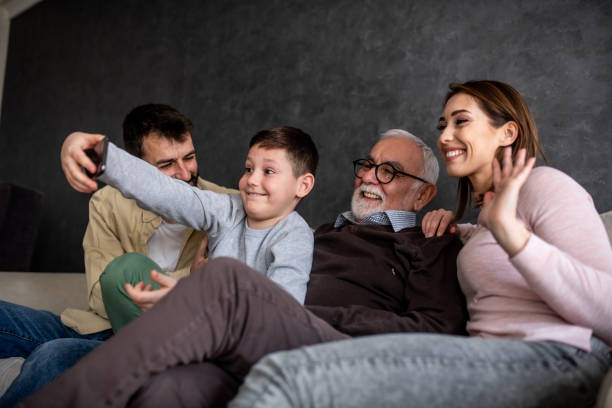 istock Grandfather and parents are posing while little boy is taking selfie with them. 1305171753