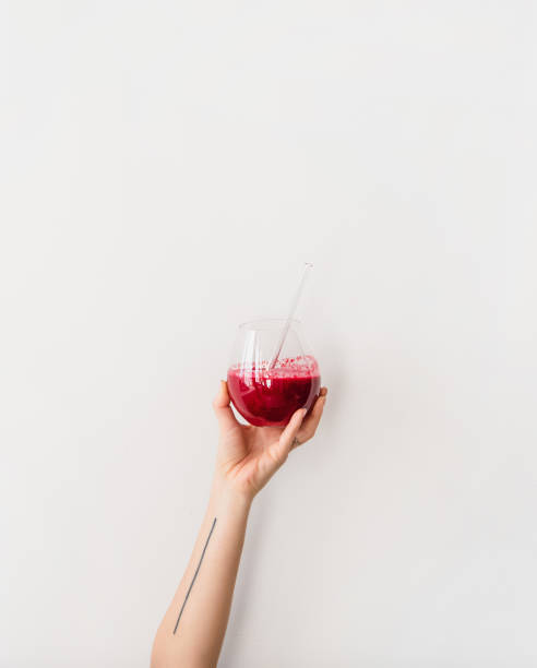istock Human hand holding glass with beet pomegranate smoothie, vertical composition 1305171769