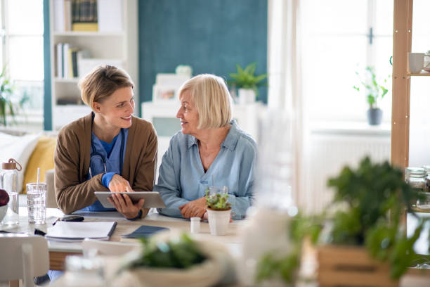 Caregiver or healthcare worker with senior woman patient, using tablet and explaining. Caregiver or healthcare worker with senior woman patient, using a tablet and explaining. assisted living stock pictures, royalty-free photos & images