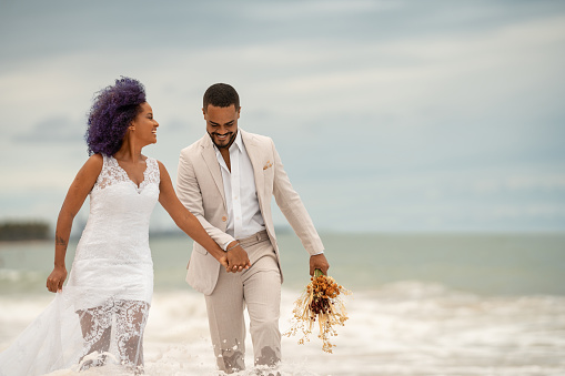 Novio y novia caminando en el borde del mar photo
