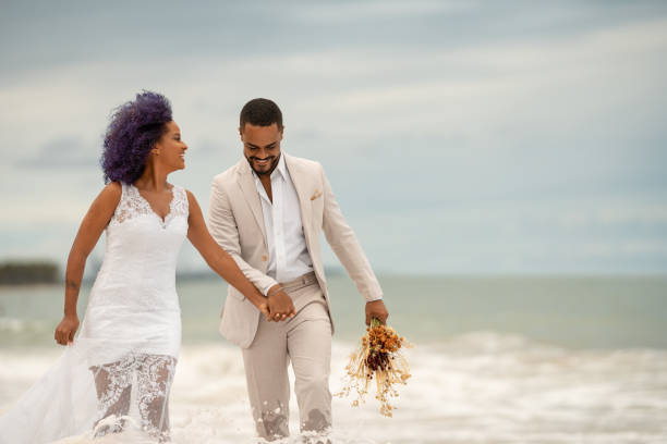 Groom and bride walking on the edge of the sea