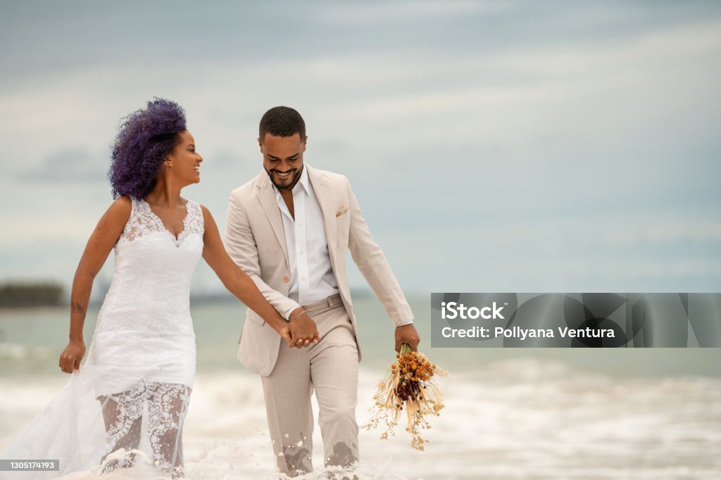 Groom and bride walking on the edge of the sea Groom, Bride, Walk on water, Beach, Newlyweds Wedding Stock Photo
