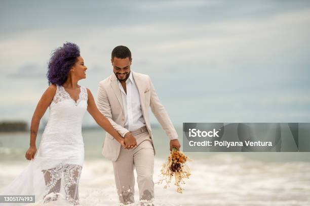 Groom And Bride Walking On The Edge Of The Sea Stock Photo - Download Image Now - Wedding, Beach, Engagement