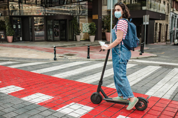 istock Young woman with a protective mask on electric scooter 1305176458