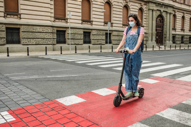 istock Young woman with a protective mask on electric scooter 1305176558