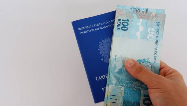 carta di lavoro brasiliana (carteira de trabalho) e denaro brasiliano su sfondo bianco. concetto di lavoro. - minimum wage foto e immagini stock