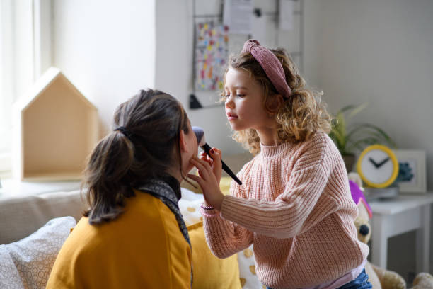 istock Sisters indoors at home, applying make-up. Lockdown concept. 1305176831