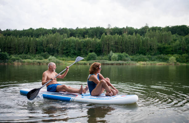 istock Senior couple paddleboarding on lake in summer. 1305179853
