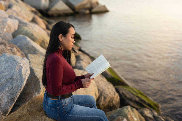 istock Beautiful young asian woman reading a book 1305179856