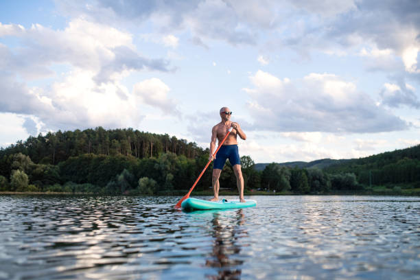 istock Senior man paddleboarding on lake in summer. Copy space. 1305179919
