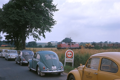 Schleswig Holstein, Germany, 1969. Motorists waiting in front of a railway barrier.
