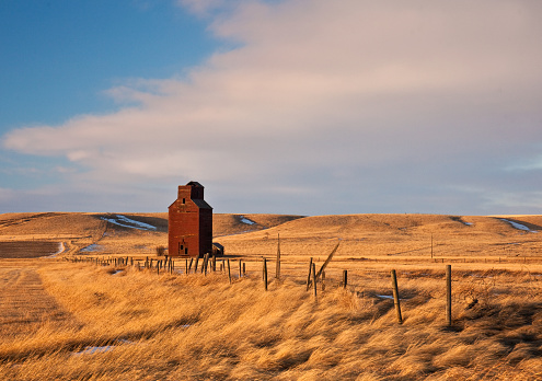 An old wooden grain elevator crumbing and abandoned on the great plains. Image taken in Saskatchewan, Canada.