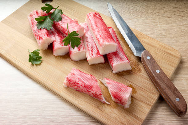 istock Appetizing crab sticks on wooden cutting board. 1305182231