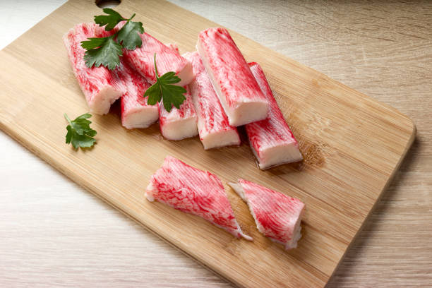 istock Appetizing crab sticks on wooden cutting board. 1305182247