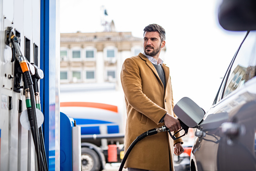 Elegant man refueling his car's tank at the gas station in the city.