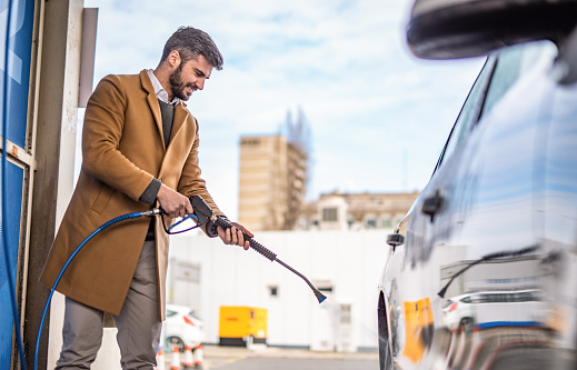 Photo of elegant man washing his car in the city.