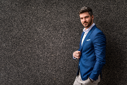 Elegant mid adult businessman standing on gray background.
