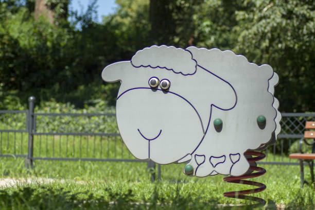 Rockers for children placed on the playground. Around it, sand to cushion a possible fall and green grass.