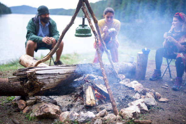 istock Group of friends having breakfast next to campfire. 1305189892
