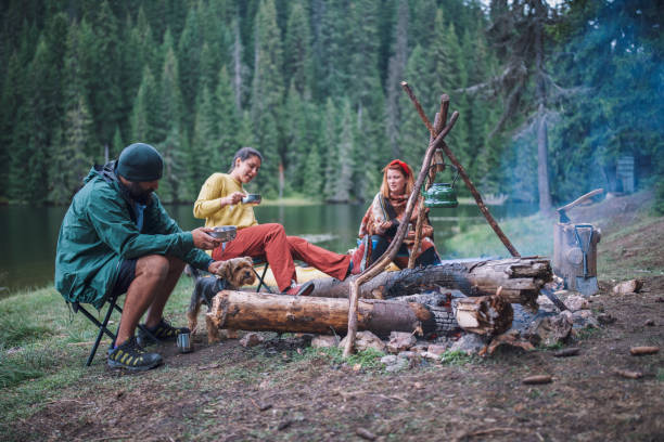 istock Group of friends having breakfast naxt to campfire. 1305189894