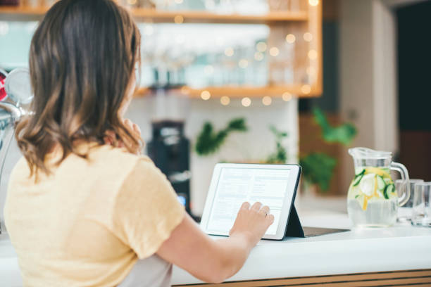 Small business management gets smarter by the day Shot of a young woman using a digital tablet while working in a cafe point of sale tablet stock pictures, royalty-free photos & images