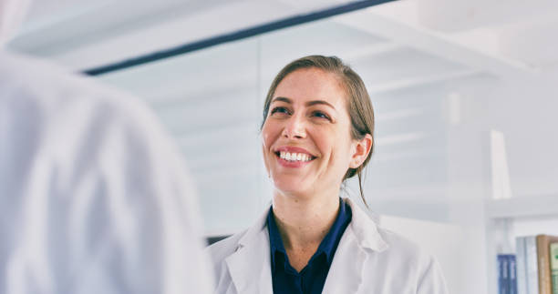 They're keen on developing research together Shot of a young woman talking to a colleague in a lab biochemist stock pictures, royalty-free photos & images