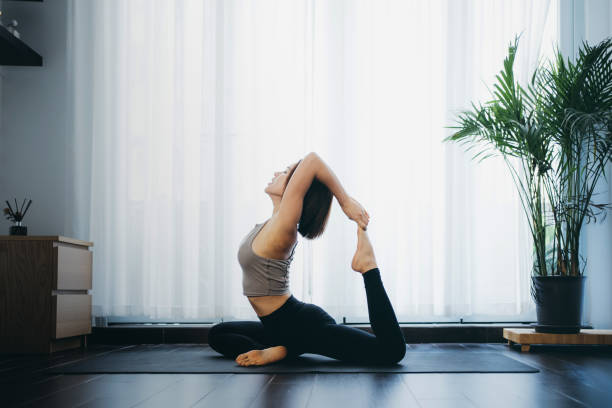 mujer practicando yoga en casa - yoga fotografías e imágenes de stock