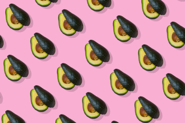 istock Avocado fruit cut in two halves, trendy  pattern on bright pink background. 1305197223