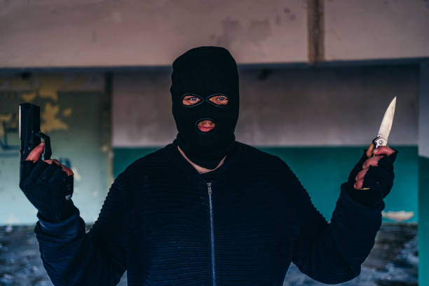 istock Man with a mask holding gun and knife in hands 1305199331