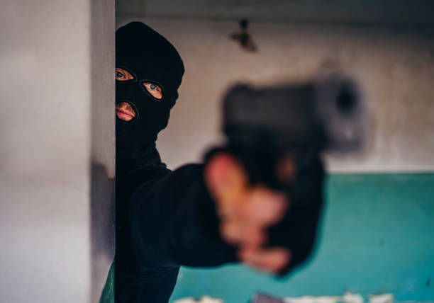 Man with a mask holding gun Caucasian man with a mask holding a gun in hand and aiming head shoot stock pictures, royalty-free photos & images